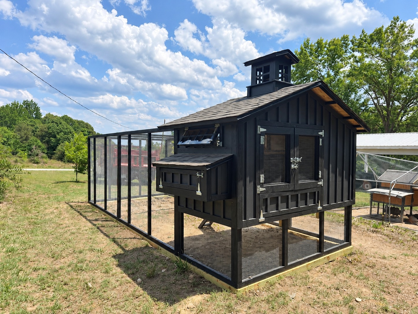 Coop exterior showing the nesting box, shingled roof, cupola, and attached run